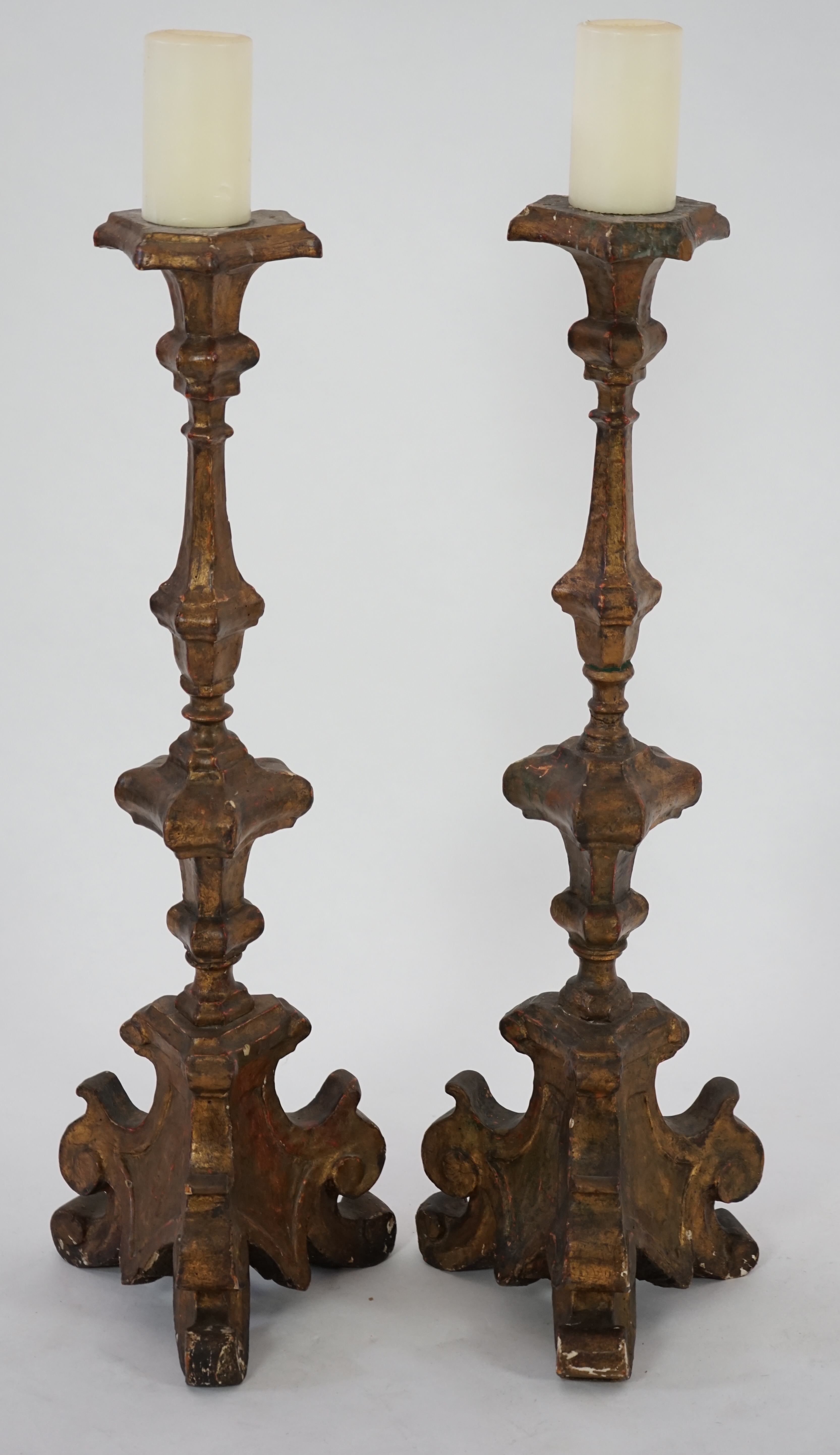 A pair of 18th century Italian giltwood candlesticks with knopped triangular stems and scroll feet, 89cm high. Condition - fair, Provenance- Brede Place, East Sussex, a former residence of the Frewen family from 1712-193